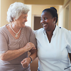 an elderly woman smiling with a caregiver on a walk