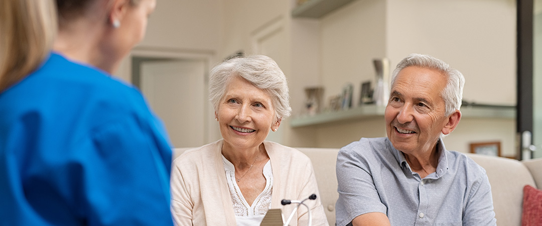 Smiling elderly couple asking a nurse a question