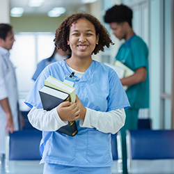 Cute smiling nurse with an armful of books